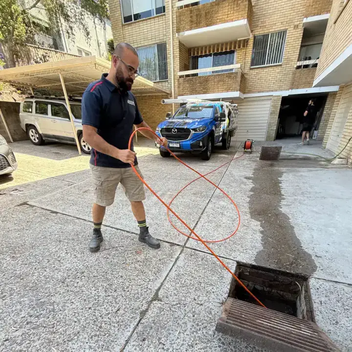 Antons plumber using professional drain-clearing equipment at an outdoor access point
