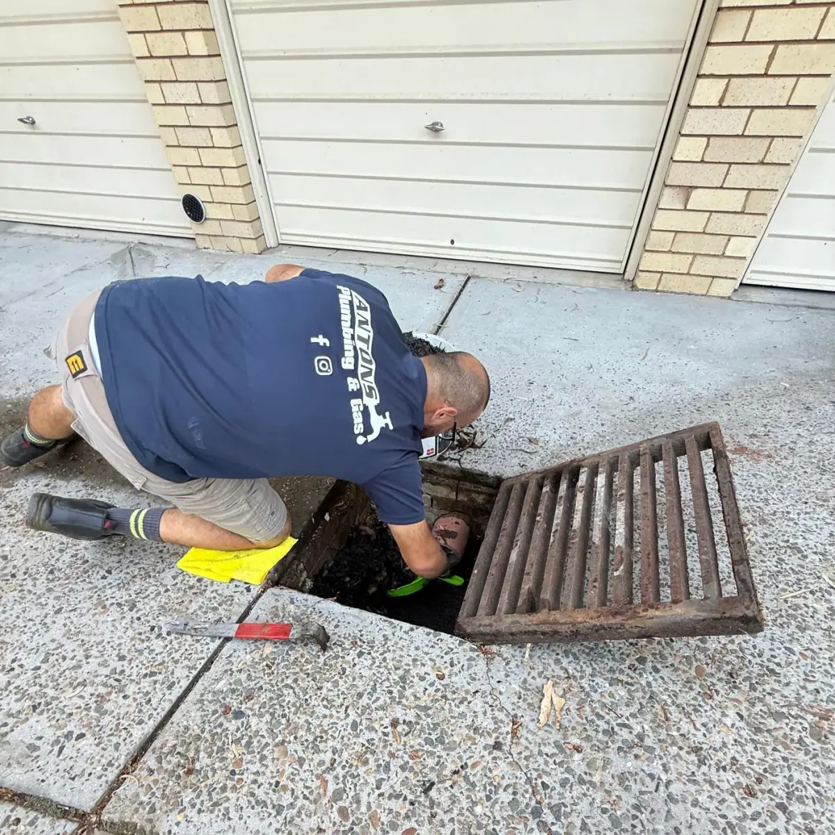 Antons plumber working inside an open outdoor drain pit